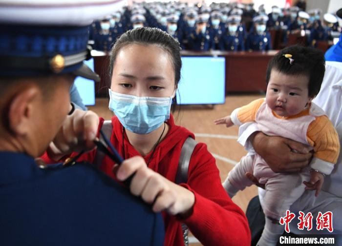 新消防員楊振的妻子彭莉與女兒現(xiàn)場見證丈夫加入“火焰藍(lán)”的神圣時(shí)刻?！⒅铱?攝